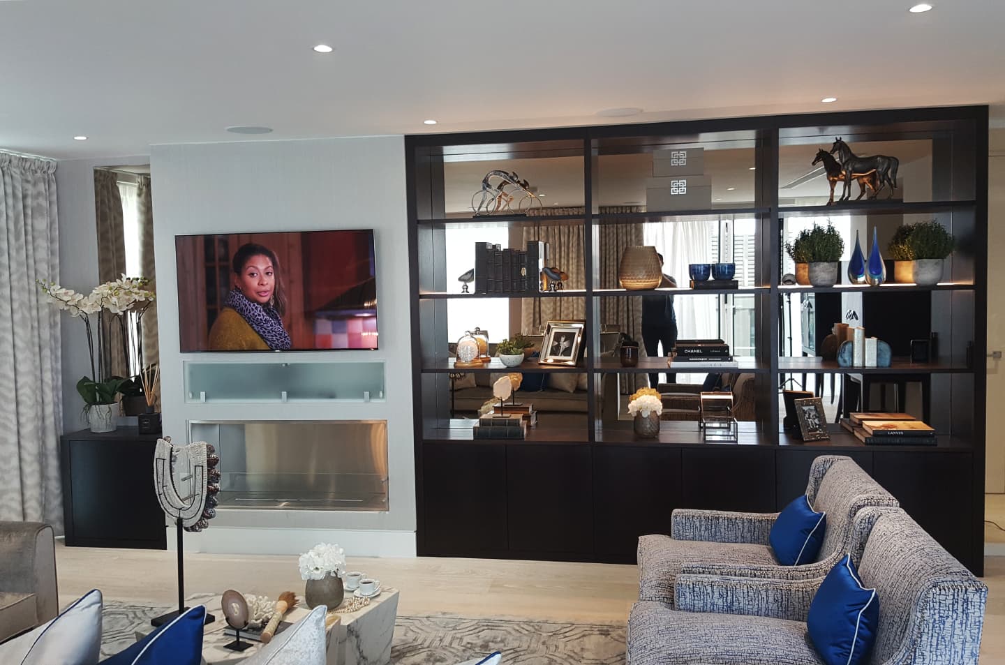 Dark fitted bookcase with illuminated display shelves and lower cupboards in Soho