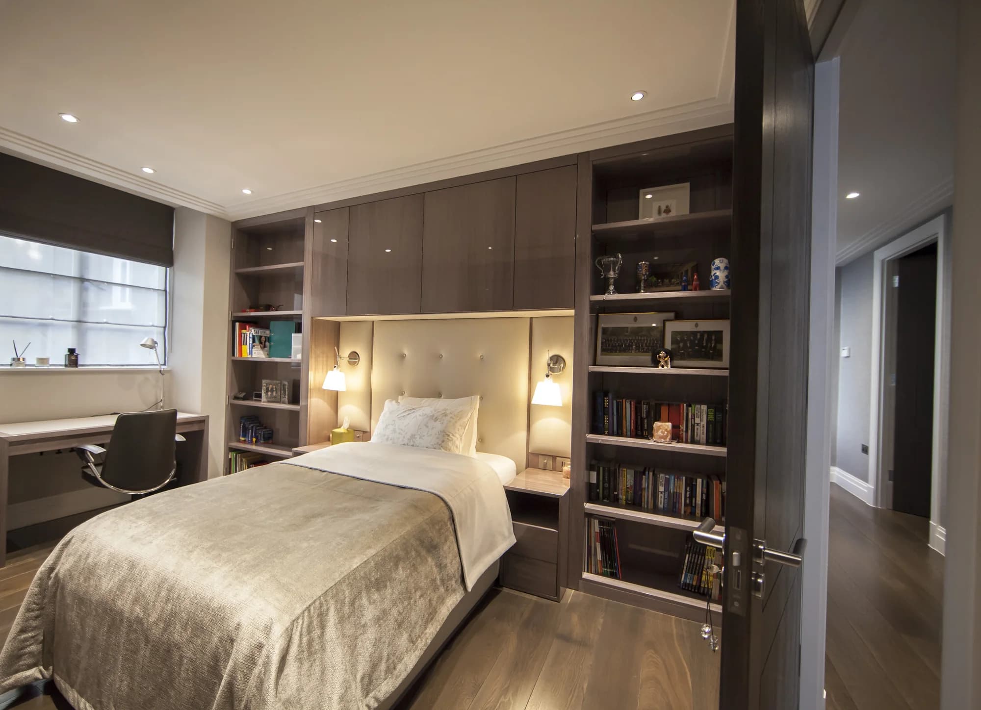 Full fitted bed wall with tall bookcases, overhead cupboards and bedside storage