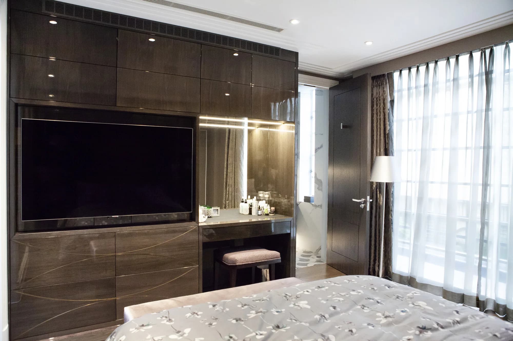 Overall bedroom TV wall with glossy cupboards and an illuminated dressing table