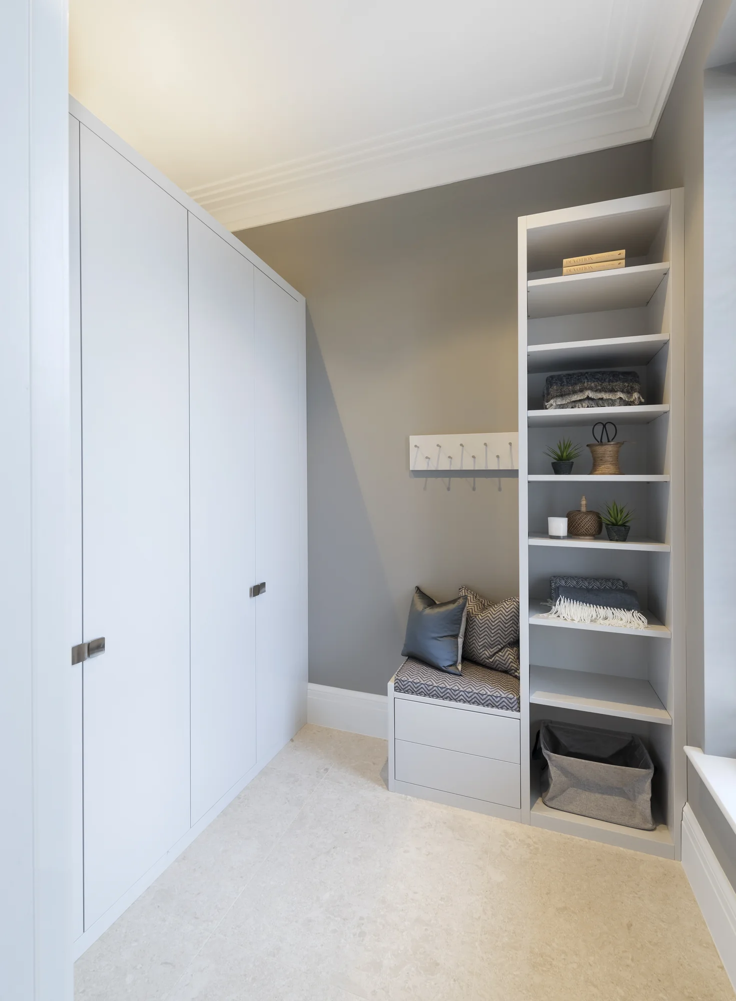 Closed pale hallway wardrobe beside a fitted bench, coat hooks and open shoe shelves