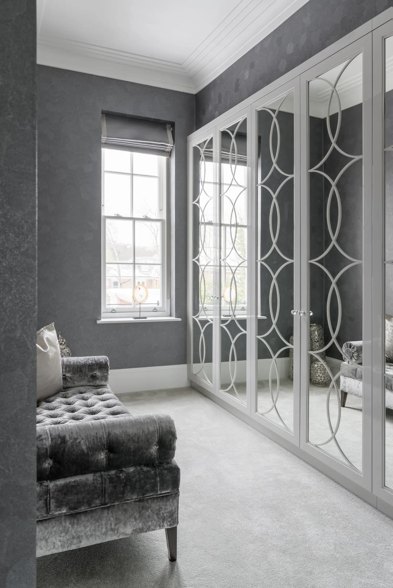 Closed mirrored wardrobe doors with pale circular patterns beside a window