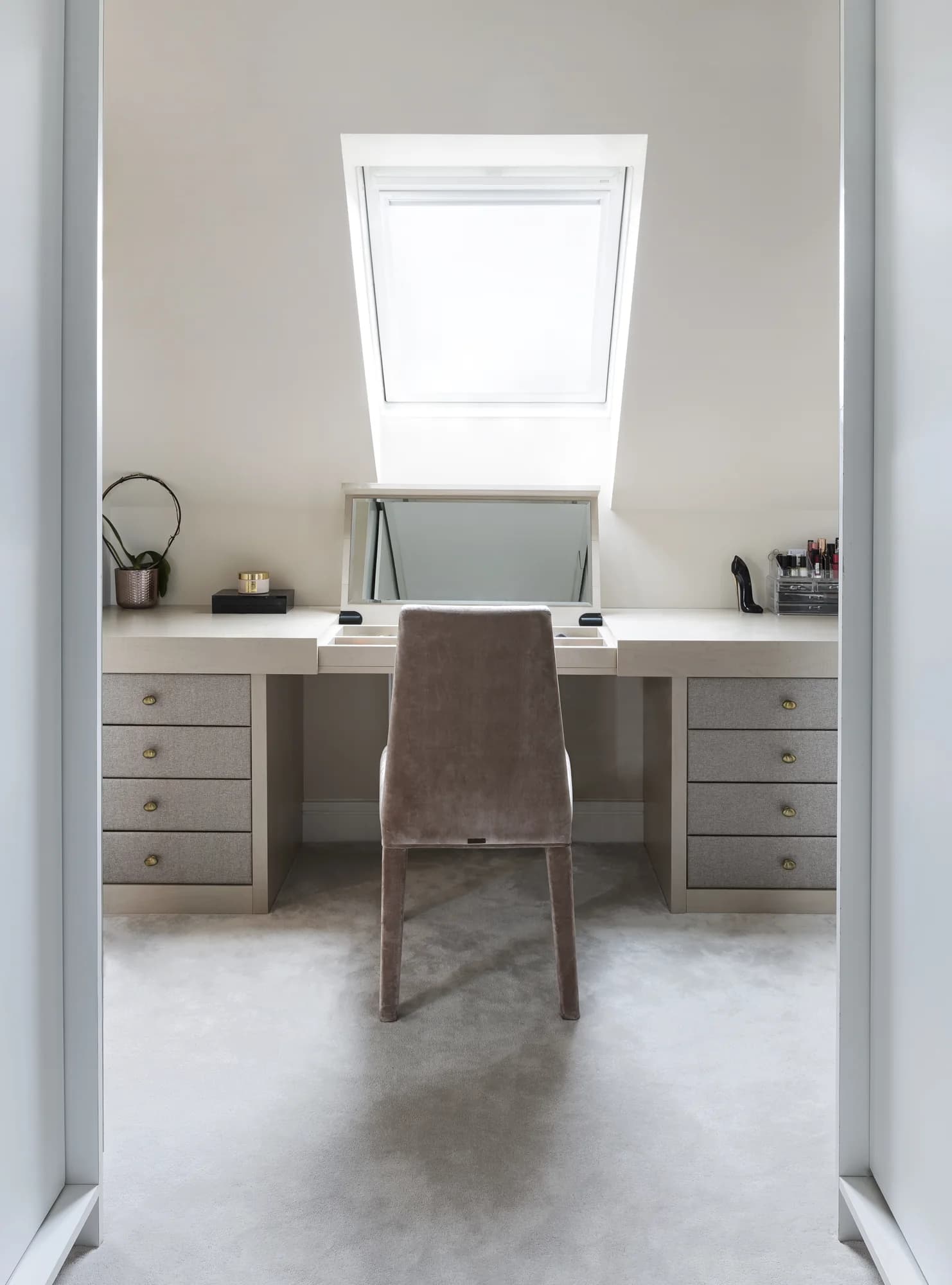 Full dressing table with drawer banks and a raised mirror beneath a rooflight