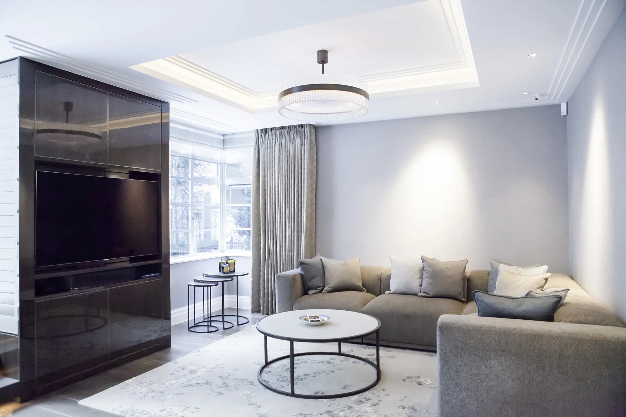 Glossy dark fitted TV wall beside the window in a light Belgravia living room