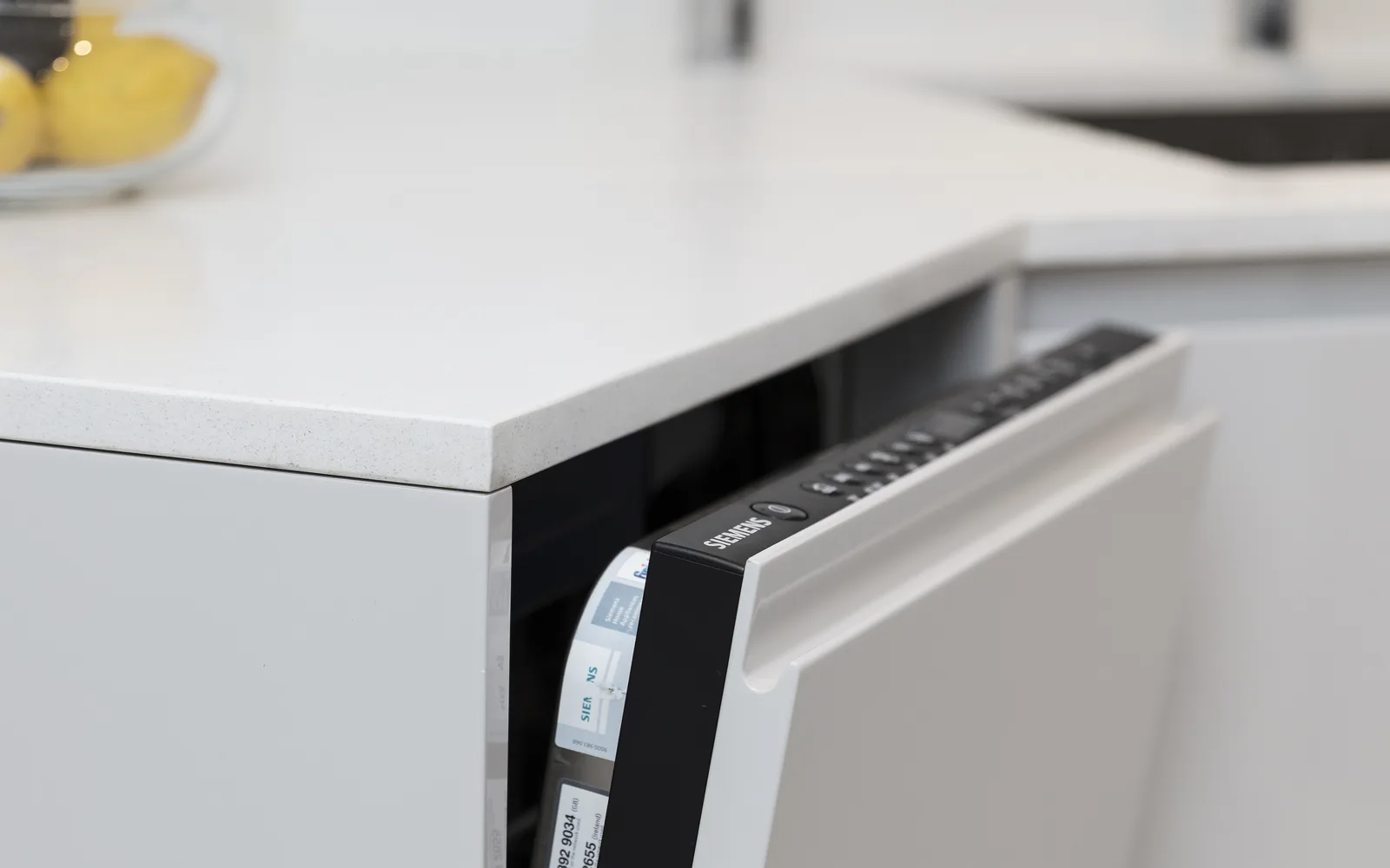 Integrated dishwasher fitted beneath a white kitchen worktop